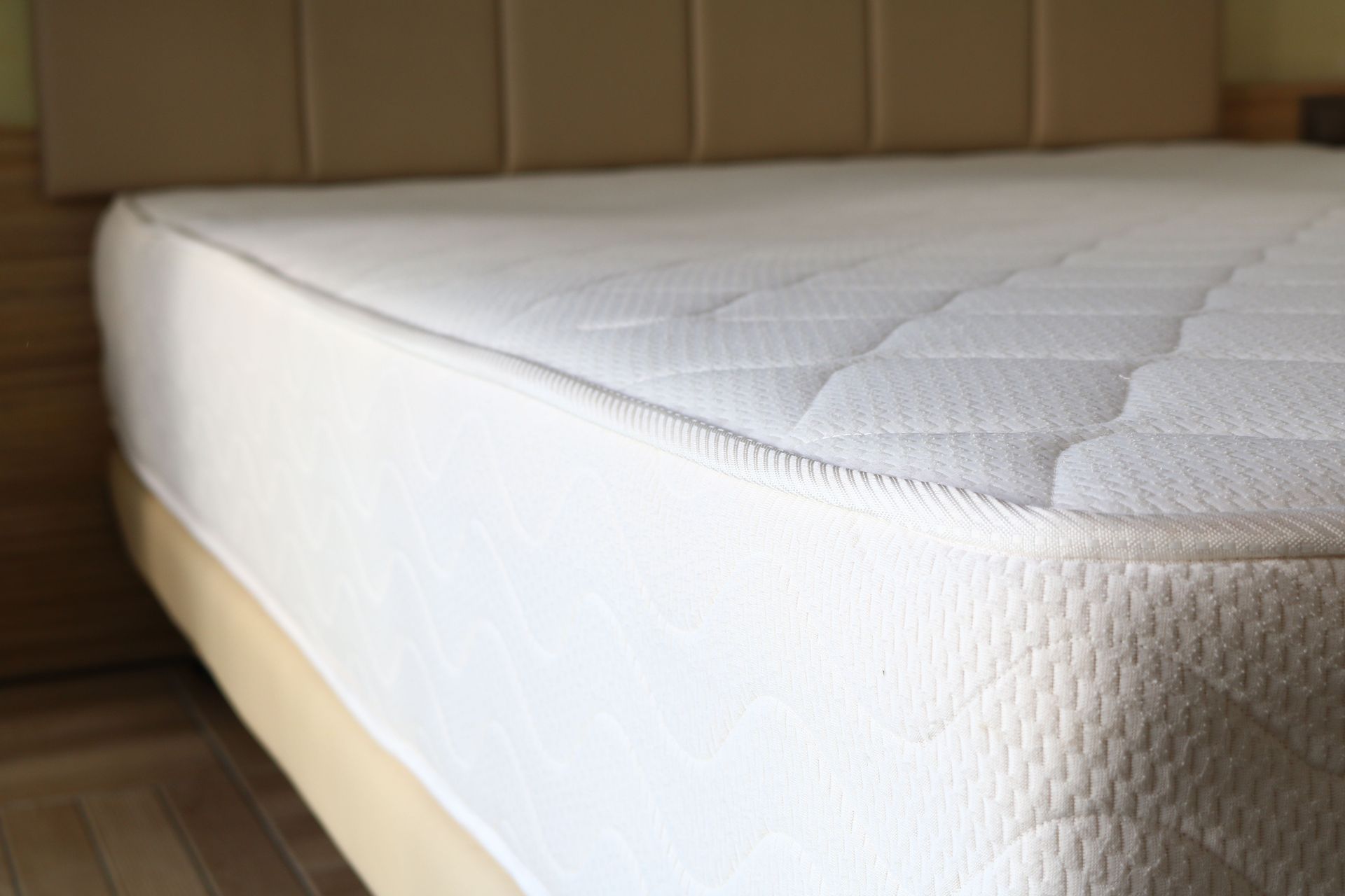 A clean white quilted mattress on a bed frame