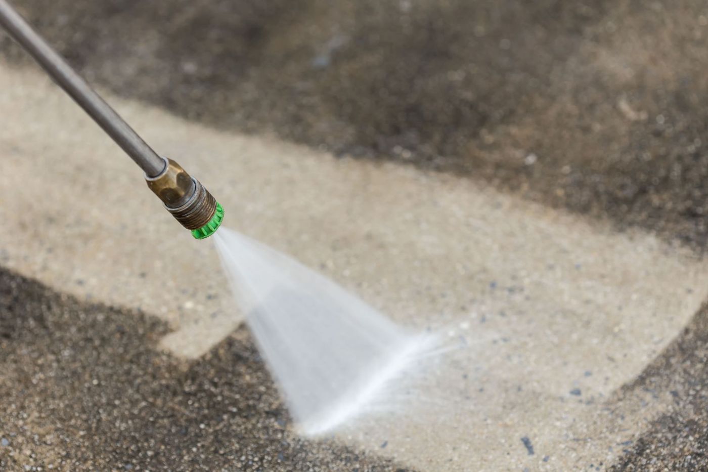 Pressure washer cleaning a stripe through dirty concrete