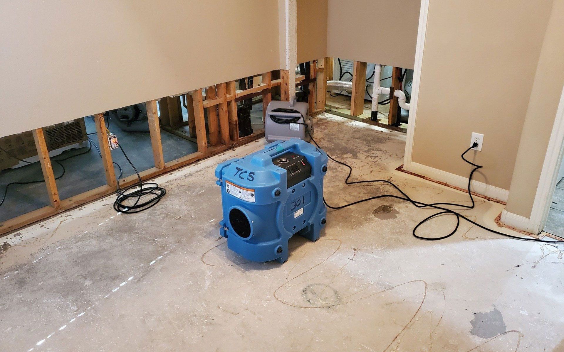 Air mover drying out a room after water damage, drywall cut back